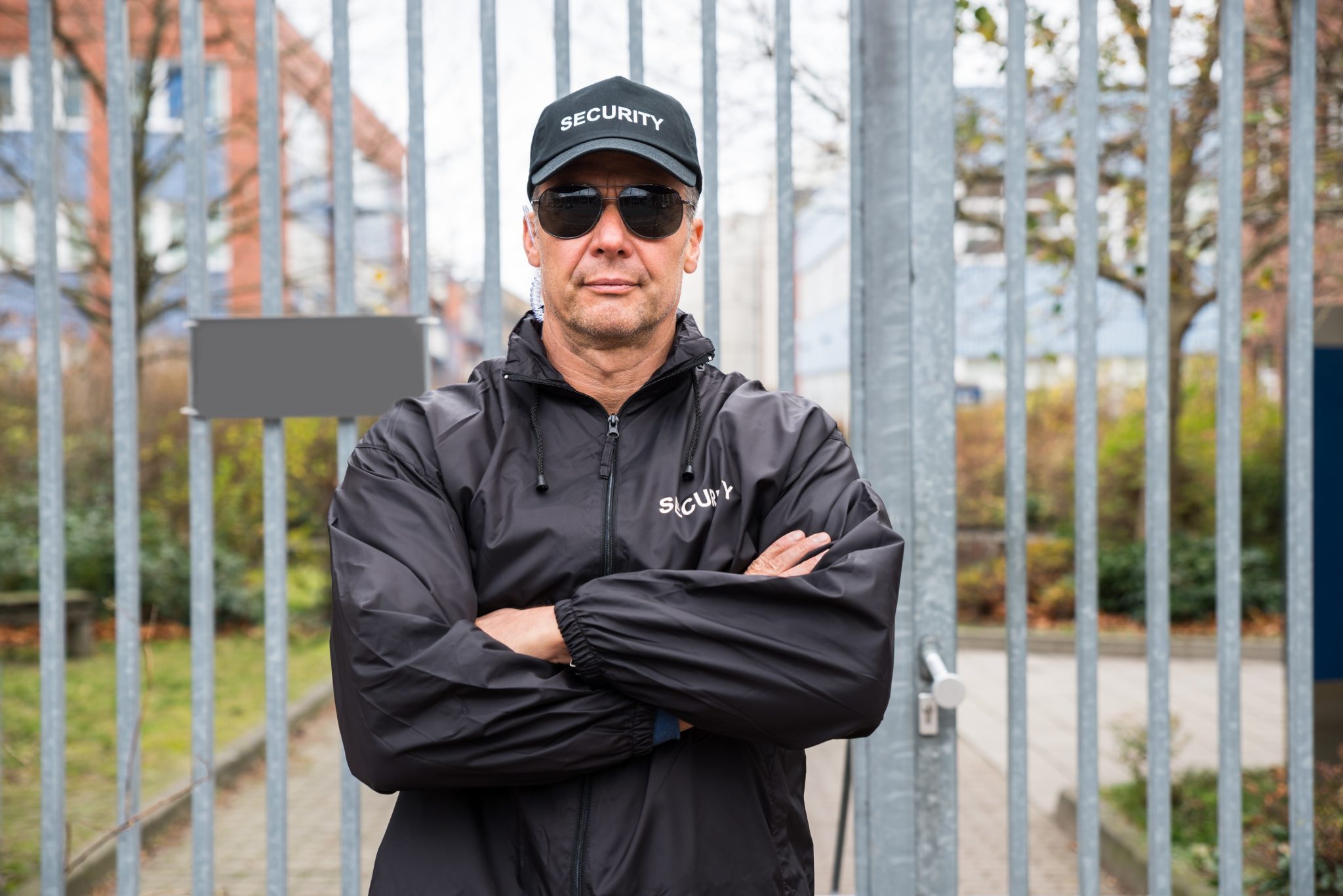 Confident security guard standing in front of a gate.